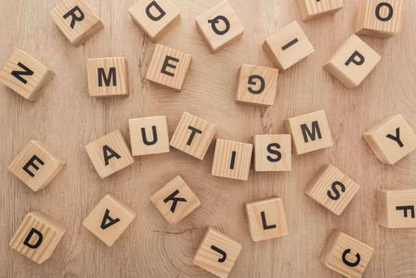 top view of autism lettering made of wooden cubes with different letters on table - 写真・画像