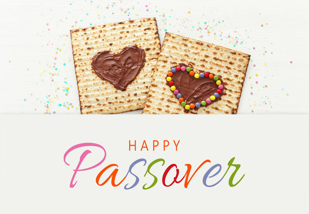 Pesah celebration concept (jewish Passover holiday) with chocolate heart and colorful candies over matzah. Top view flat lay - Photo, image