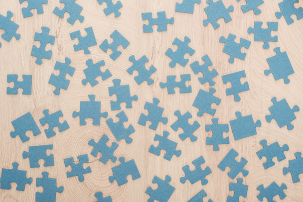 pohled shora modré puzzle částí roztroušených na dřevěný stůl - Fotografie, Obrázek