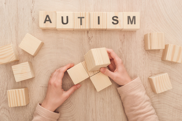 cropped view of woman holding empty wooden cubes with copy space near autism lettering - Foto, immagini
