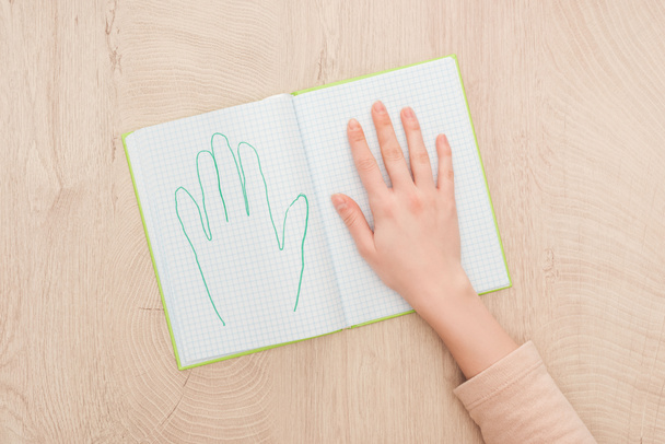 cropped view of female hand on opened notebook with drawn human palm - Фото, зображення