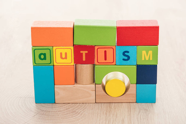 autism lettering made of colorful building blocks on wooden surface - Фото, зображення