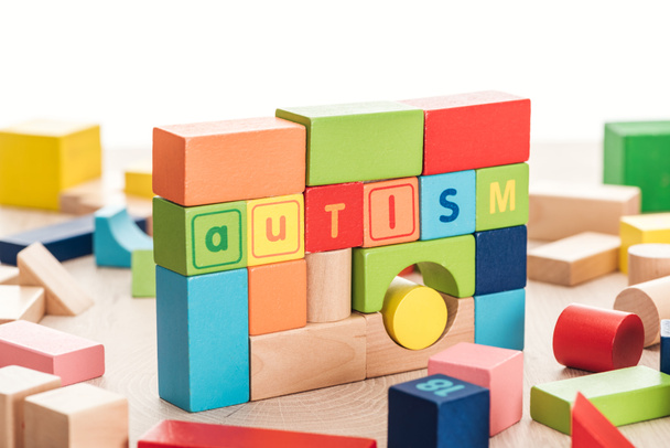 autism lettering made of colorful building blocks on wooden surface isolated on white - Photo, Image