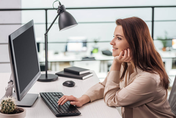 happy young woman typing on computer keyboard at workplace in modern office - Photo, Image