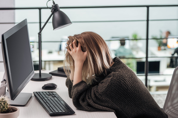 depressief meisje zit op werkplek met handen op kop in moderne kantoren - Foto, afbeelding