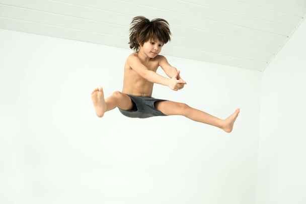 Zıplayan saçı kabarık bir çocuk ve elleri beyaz bir arka planda hedef alınmış bir silahla bağlanmış bir çocuk. - Fotoğraf, Görsel