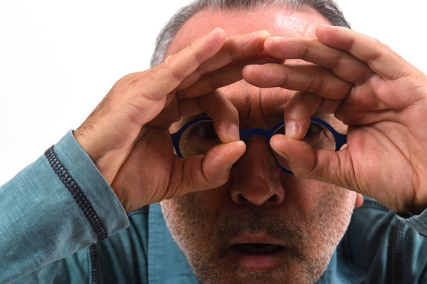 Mann blickt durch Finger, als trage er eine Brille auf weißem Rücken - Foto, Bild
