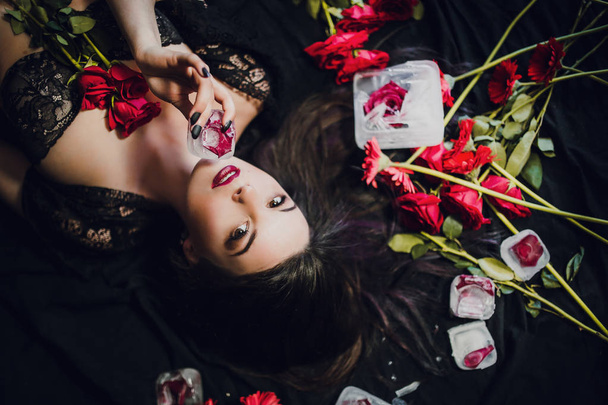 young woman in black lingerie posing with red rose frozen in ice - Foto, Imagem