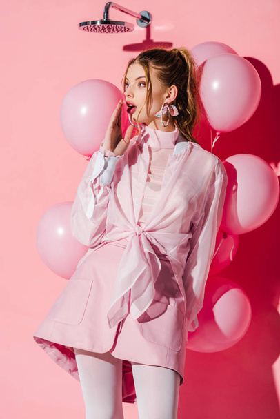 mujer sorprendida sosteniendo globos de aire mientras está de pie en rosa
 - Foto, imagen