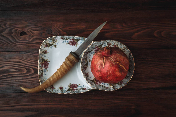 pomegranate and knife on a dark wooden background - Foto, Imagem