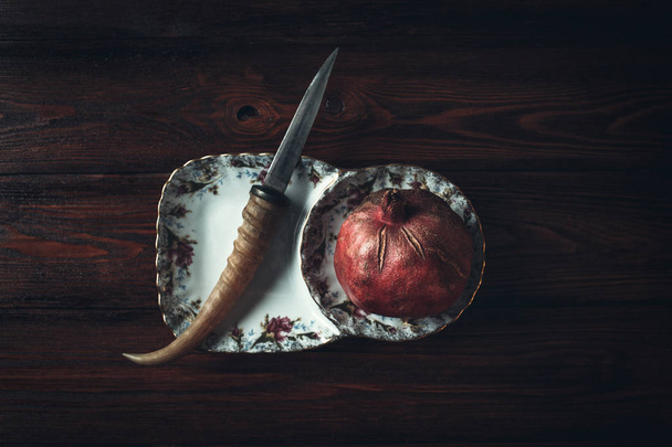 pomegranate and knife on a dark wooden background - Foto, Imagem