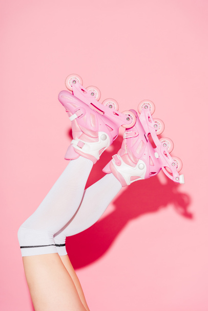 bijgesneden weergave van meisje dragen lange sokken en skates op roze - Foto, afbeelding