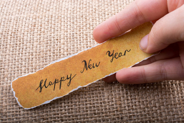 手で引き裂かれた黄色の紙に書かれた幸せな新年 - 写真・画像
