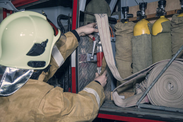 Пожарная машина готова к реагированию на чрезвычайные ситуации, пожарный проверяет спецназ
 - Фото, изображение