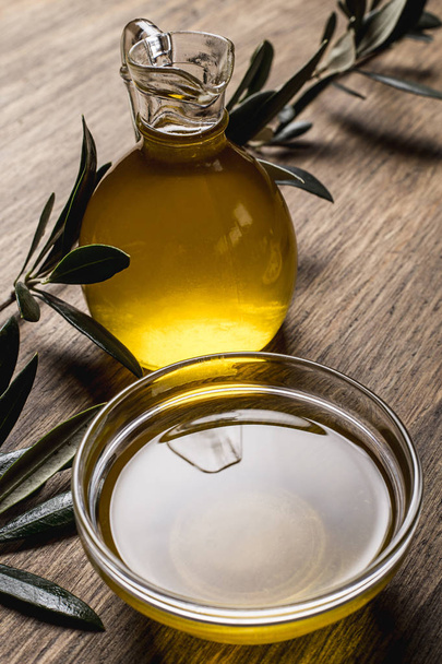 Olive oil, leaves on a wooden table - Foto, Imagen
