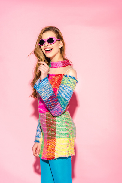cheerful young woman smiling in sunglasses and checkered dress on pink - Foto, Imagem