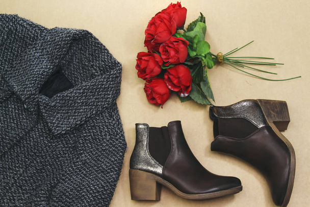 Ensemble de vêtements d'automne et d'hiver pour femmes : veste grise, bottes brunes et bouquet de fleurs. Vêtements à la mode pour les promenades, pose plate
 - Photo, image
