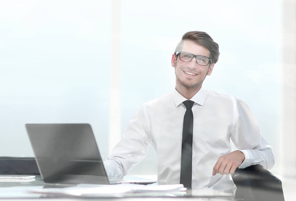 smiling young businessman sitting in a spacious office - Fotografie, Obrázek