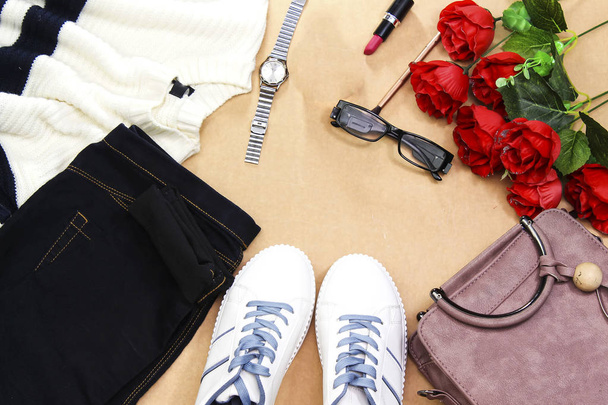 Колекція жінки: сині джинсові та білі кросівки з синіми шнурками та зеброю вовняний светр, рожевий ручний мішок, троянди квіти, окуляри, пляшка парфумів, помада, пензлик та ручний годинник
. - Фото, зображення