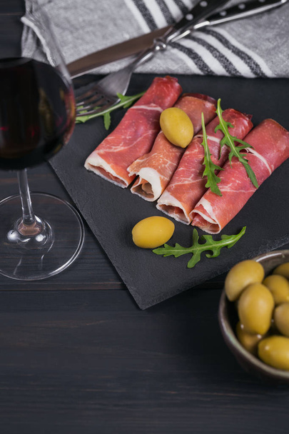 Black stone platter with slices of cured ham or Spanish jamon se - Fotó, kép