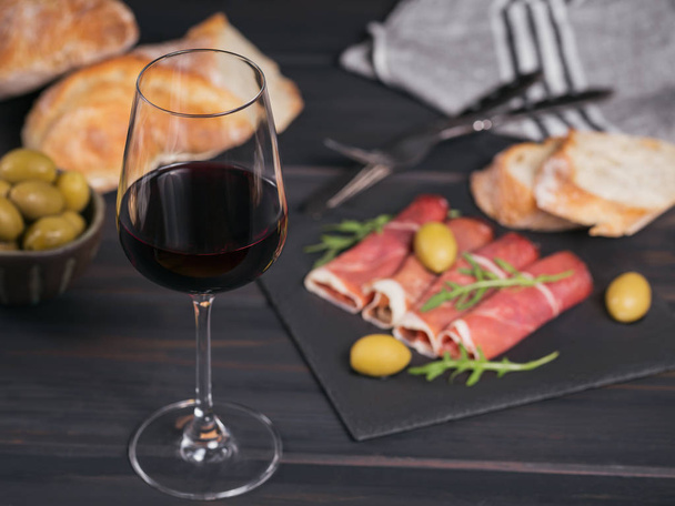 Glass of red wine with slices of cured ham or Spanish jamon serr - Φωτογραφία, εικόνα