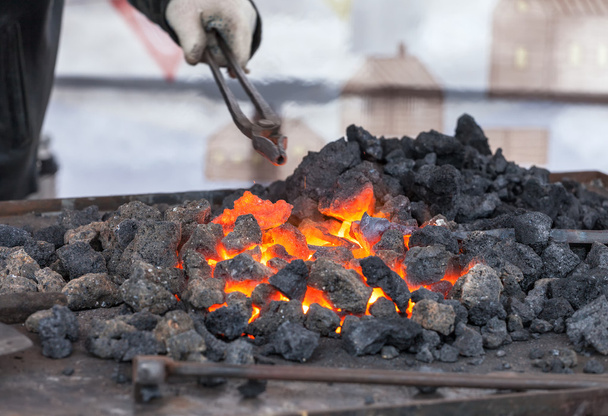 Ferreiro forja um ferro vermelho-quente na forja
 - Foto, Imagem