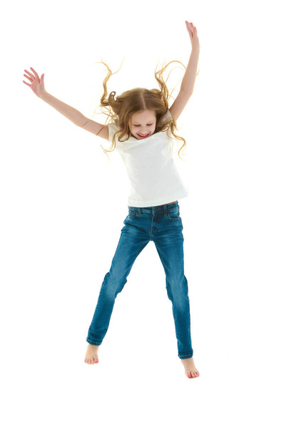 A little girl in a pure white t-shirt is jumping. The concept of - Foto, Imagen