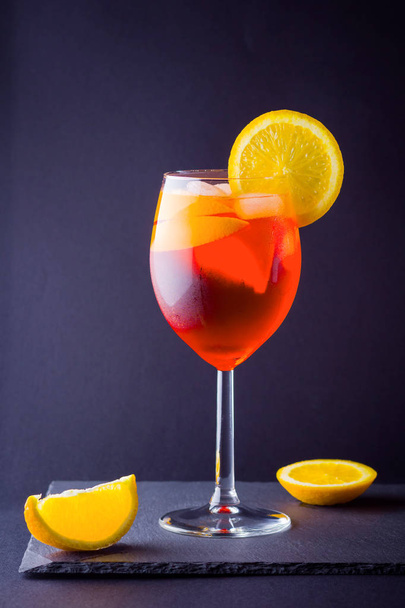 Cocktail aperol spritz op donkere achtergrond. Zomer cocktail met oranje segmenten van de alcohol. Italiaanse cocktail aperol spritz op leisteen bord. Trendy drank - Foto, afbeelding