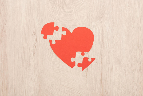top view of bright paper heart and pieces of puzzle on wooden background  - Photo, Image