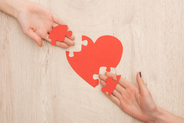 cropped view of women holding pieces of puzzle and paper heart  - Fotografie, Obrázek