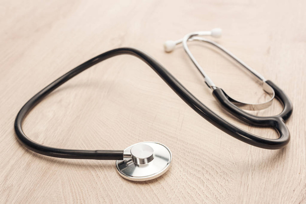 selective focus of stethoscope on wooden and white table  - Fotografie, Obrázek