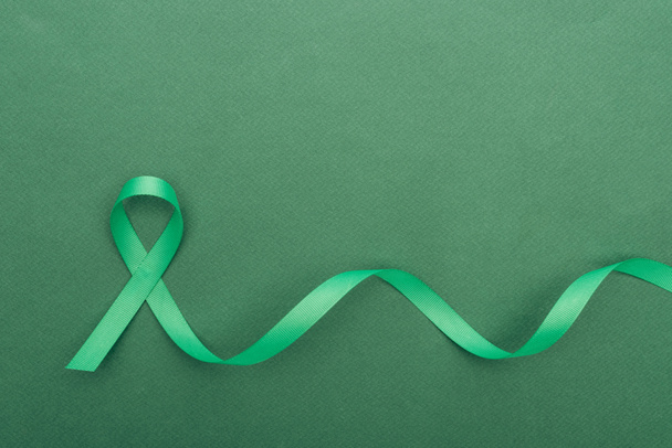 top view of green and colorful ribbon on green background with copy space   - Valokuva, kuva