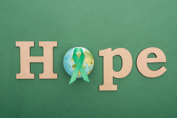 vista superior de la palabra de madera esperanza, tierra de juguete y cinta verde sobre fondo colorido
  - Foto, Imagen