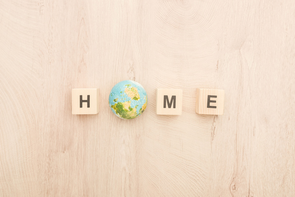 top view of cubes with home lettering and toy planet on wooden background  - Fotó, kép