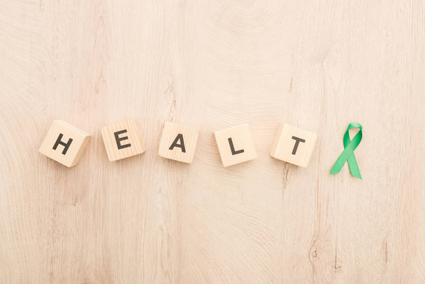 top view of cubes with health lettering and green ribbon on wooden background  - Foto, imagen