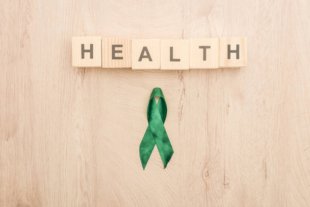 top view of cubes with health lettering and green ribbon on wooden background  - 写真・画像