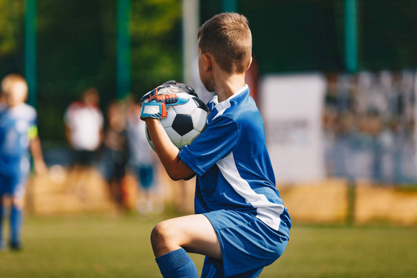 Fiatal Soccer kapus kapus elkapta a labdát. Fiatal fiú futball kapus - Fotó, kép