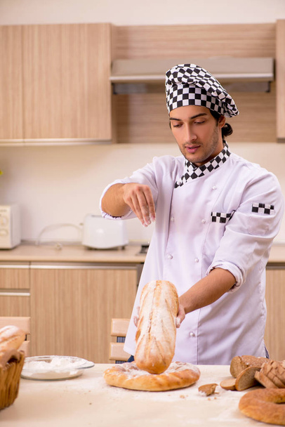 Young male baker working in kitchen - Zdjęcie, obraz