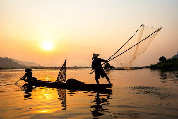 Asie filet de pêcheur en utilisant sur bateau en bois coulée coucher de soleil ou su
 - Photo, image