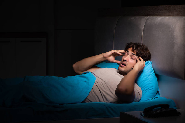 Mladý pohledný muž trpící nespavostí v posteli - Fotografie, Obrázek