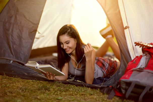 girl reading a book in tent on camping - Foto, afbeelding