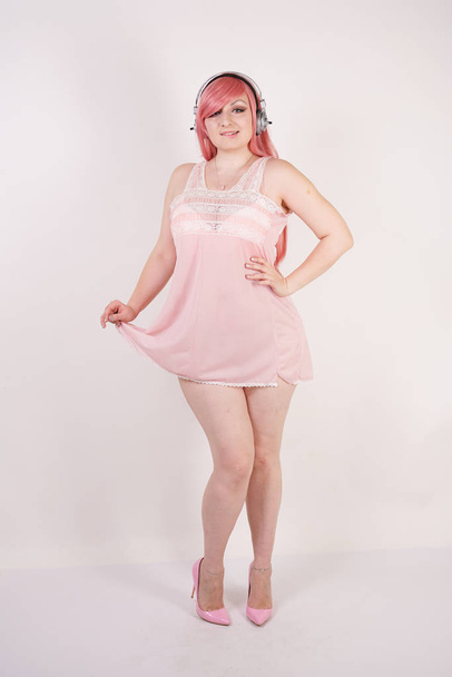 Vrij volwassen vrouw met mollig lichaam dragen van lingerie babydoll roze jurk met hakken en permanent op witte studio achtergrond alleen - Foto, afbeelding