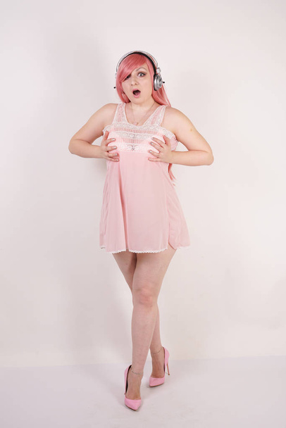 hübsche erwachsene Frau mit molligem Körper trägt Dessous Babydoll rosa Kleid mit Absätzen und steht auf weißem Studiohintergrund allein - Foto, Bild