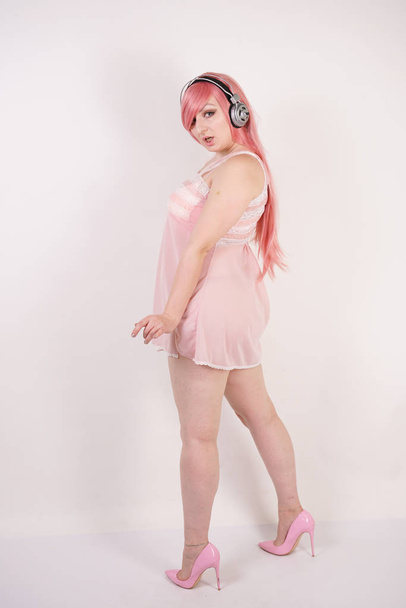 Pretty adult woman with chubby body wearing lingerie babydoll pink dress with heels and standing on white studio background alone - Φωτογραφία, εικόνα