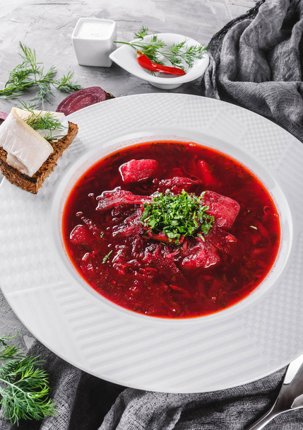 Traditionelle ukrainische und russische Rote-Bete-Suppe - Borschtsch im Teller mit Gewürzen, Knoblauch, Gemüse auf rustikalem Hintergrund, gesunde Ernährung. Zutaten auf den Tisch. Draufsicht, flache Lage - Foto, Bild