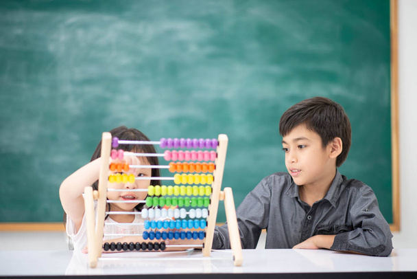 Studenci chłopiec i dziewczyna pochylony matematyki w klasie Pokój Montessori  - Zdjęcie, obraz