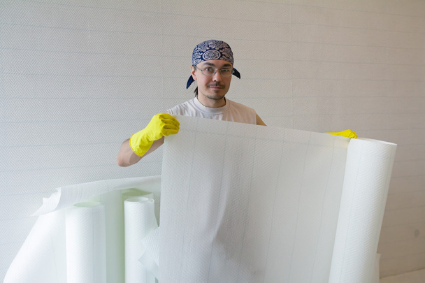 Young worker holding roll of wallpaper - Foto, Imagen