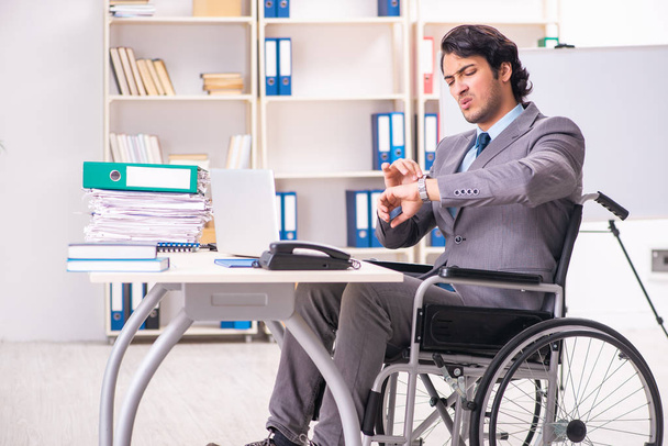 Genç yakışıklı çalışan tekerlekli sandalyeye mahkum ofiste - Fotoğraf, Görsel