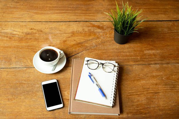 Coffee up and notebook, pen with glasses, cell phone on wooden table. - Photo, Image