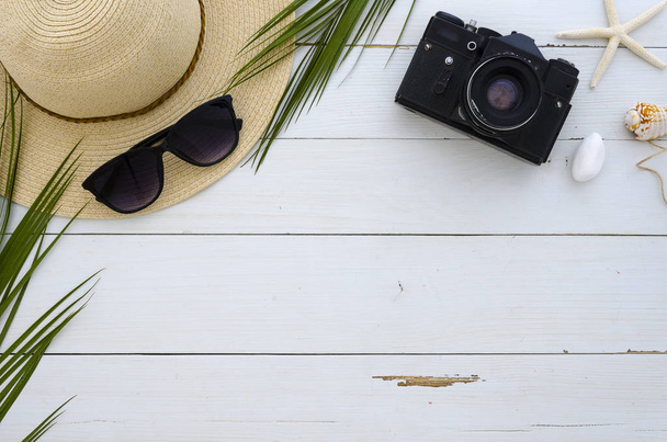 Letní prázdniny, cestování, dovolená, pláže koncept. Sluneční klobouk, sluneční brýle a tropical palm listy na dřevěné desce bílé barvy. Pohled shora, prostor pro text. Plochou ležel mock-up - Fotografie, Obrázek